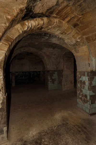 An old abandoned tunnel in an underground wine cellar. Entrance to catacombs. Dungeon Old stone fortress. As creative background for staging dark design. Mystical interior of ancient dungeon