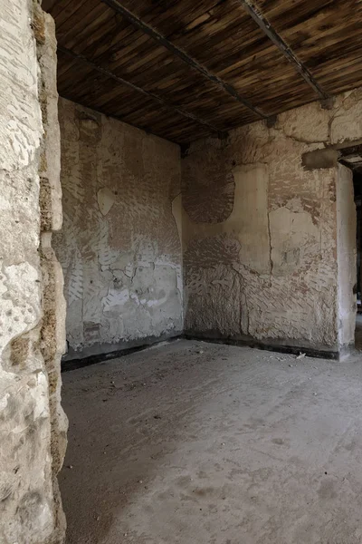 Mystical interior, ruins of facade of abandoned ruined building of ancient castle, mansion. Old ruined walls, corridor with garbage and mud. Ruins Ancient historical building, destroyed by vandals