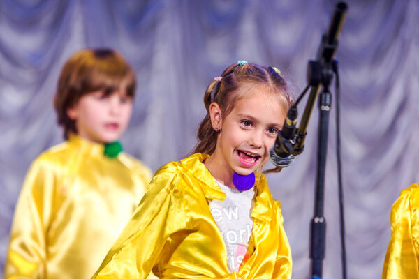 Odessa, Ukraine - December 24, 2015: Children's musical groups singing and dancing on stage in bright colorful clothes. Emotional, touching children's musical stage show.