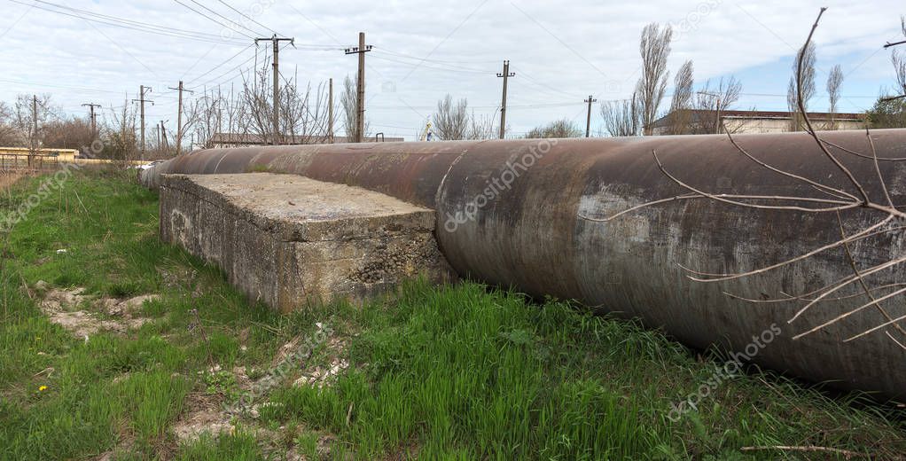 An old rusty large iron pipe of an outdated industrial waterpipe, Odessa, Ukraine, 2018. Large worn-out iron pipes for water supply of the city