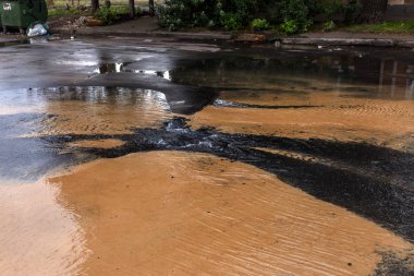 Su temini, kanalizasyon kaza. Asfalt boşlukta altından kirli kanalizasyon Su Çeşmesi döktü. Atılım kanalizasyon sistemine. Su akar kanalizasyon kapağı yoldan aşağı