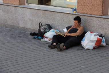 Odessa, Ukrayna - 12 Ağustos 2017: Sokakta evsiz dilenci. Evsiz, kirli yaşlı kadın, eşyaları ve yemekleri ile sokak asfaltında yatıyor. Sosyal sorun. Dilenciler işsiz peopl vardır