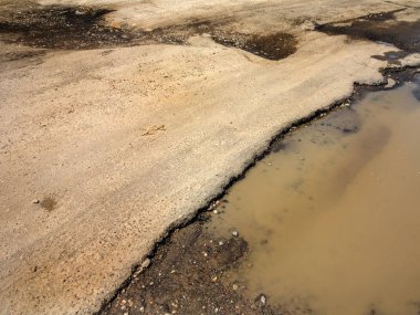 Asfalt yol ile çukurların dondurma ve çözme döngüsü sırasında belgili tanımlık kış nedeniyle zarar görmüş. Zavallı yol.