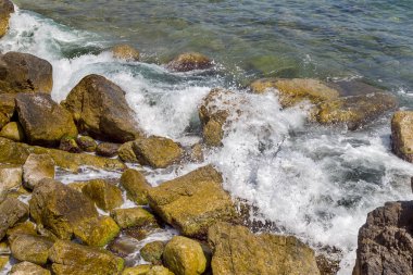 Büyük dalga sıçrama. Deniz suyu kayalar ve kayalıklarla karşı yenerek. Yukarıda ferahlatıcı güneş Zenit Beach'te mavi gökyüzü okyanus su damla.