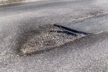 Asfalt yol ile çukurların dondurma ve çözme döngüsü sırasında belgili tanımlık kış nedeniyle zarar görmüş. Zavallı yol.