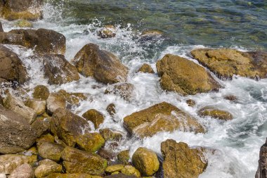 Büyük dalga sıçrama. Deniz suyu kayalar ve kayalıklarla karşı yenerek. Yukarıda ferahlatıcı güneş Zenit Beach'te mavi gökyüzü okyanus su damla.