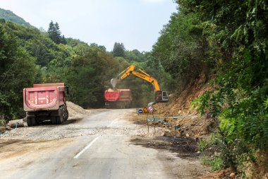 Rila Manastırı, Bulgaristan - 30 Temmuz 2016: dağ yolu genişletmek için inşaatı işi. Modern yol yapım ekipmanları çalışır. Dar geçit. Kapalı yol. Karayolu onarım çalışmaları