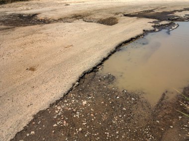 Asfalt yol ile çukurların dondurma ve çözme döngüsü sırasında belgili tanımlık kış nedeniyle zarar görmüş. Zavallı yol.