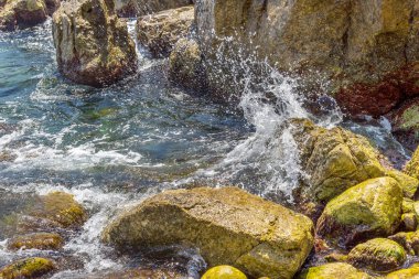 Büyük dalga sıçrama. Deniz suyu kayalar ve kayalıklarla karşı yenerek. Yukarıda ferahlatıcı güneş Zenit Beach'te mavi gökyüzü okyanus su damla.