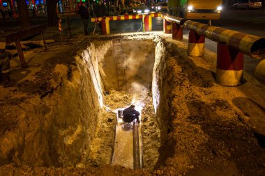 Odessa, Ukrayna - 10 Aralık 2015: inşaat işçileri Acil Onarım kentsel Karayolları geceleri mühendislik yapıyor. Onarım ve yedek su, Kanalizasyon borular alt kısmında derin bir siper gece boyunca. Kaza.