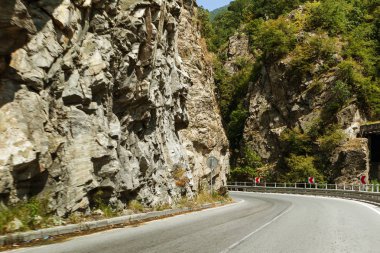 Dolambaçlı bir dağ yolu. İki yönlü yol dağlarda. Kayalık yamaçlarda taş yakınlarındaki dağlık bir alanda asfalt karayolu