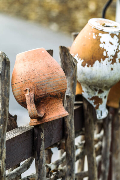 Смежные структуры веток и палочек в старинной деревянной сельской ограде с креативными предметами домашнего обихода - старые глиняные горшки для приготовления пищи в качестве модного абстрактного фона для дизайна
