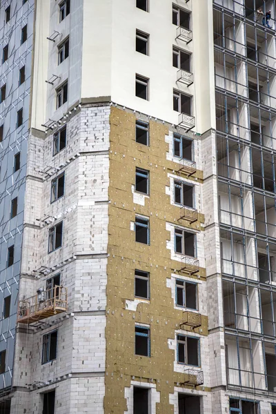 ODESSA, UKRAINE - JUNE 18 2014: Construction of a high-rise residential building works on the outer facade of the building insulation, insulation. Modern technology in the construction of thermal insulation