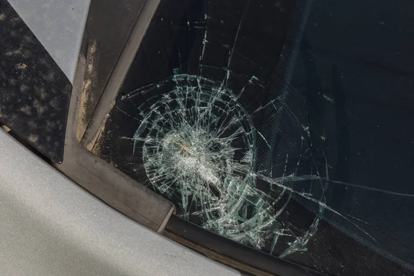 Broken car windshield. Stones on a dirty road from under the wheels at a speed smash car glass. Criminal incidents. Vandals, hooligans mutilated the car, smashed the windshield