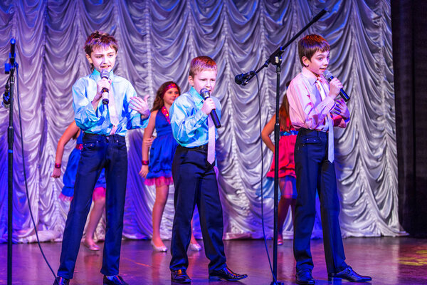Odessa, Ukraine - December 24, 2015: Children's musical groups singing and dancing on stage in bright colorful clothes. Emotional, touching children's musical stage show.