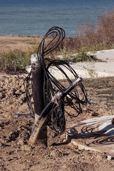 Output of electrical, signal telephone cables and fiber optic cable from earth trench near switching well. Telephone cable and telephone lines. Otic-fiber switching systems