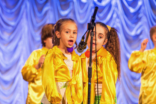 Odessa, Ukraine - December 24, 2015: Children's musical groups singing and dancing on stage in bright colorful clothes. Emotional, touching children's musical stage show.