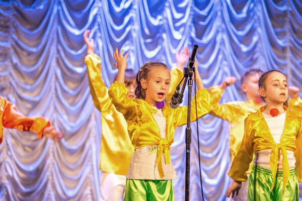 Odessa, Ukraine - December 24, 2015: Children's musical groups singing and dancing on stage in bright colorful clothes. Emotional, touching children's musical stage show.