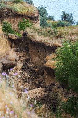Çevreye zararlı bir bölgede dağ heyelan. Yeryüzündeki büyük çatlaklar, toprak yolu kapatan büyük katmanların inişi. Dağ yamacının yamacında baraj tehlikesi