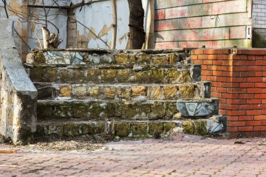 Eski, açık, taştan bir merdiven. Taş, eski merdivenlerin çimento basamaklarında yıpranma ve yıpranma izleri var. Eski taş bir merdiven, eski kırık basamaklar. Seçici odak