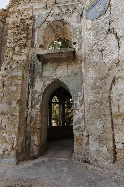 Mystical interior, ruins of facade of abandoned ruined building of ancient castle, mansion. Old ruined walls, corridor with garbage and mud. Ruins Ancient historical building, destroyed by vandals