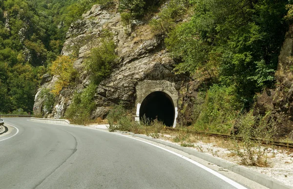 A winding mountain road. Two-way road in the mountains. Paved highway in a mountainous area near the rocky slopes of stone