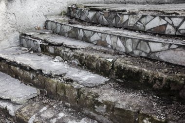 Eski, açık, taştan bir merdiven. Taş, eski merdivenlerin çimento basamaklarında yıpranma ve yıpranma izleri var. Eski taş bir merdiven, eski kırık basamaklar. Seçici odak