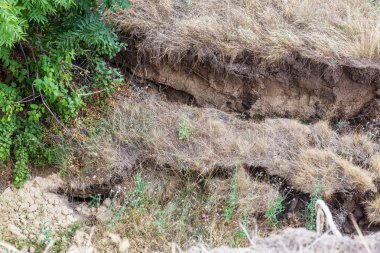 Çevreye zararlı bir bölgede dağ heyelan. Yeryüzündeki büyük çatlaklar, toprak yolu kapatan büyük katmanların inişi. Dağ yamacının yamacında baraj tehlikesi