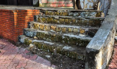 Eski, açık, taştan bir merdiven. Taş, eski merdivenlerin çimento basamaklarında yıpranma ve yıpranma izleri var. Eski taş bir merdiven, eski kırık basamaklar. Seçici odak