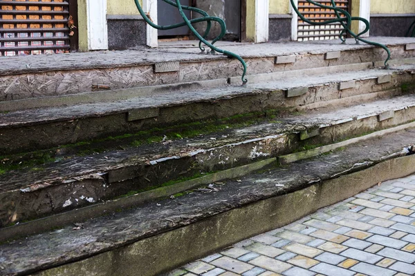 An old open outer stone staircase. Stone, cement steps of the old staircase with traces of weathering and destruction. An ancient stone staircase, ancient broken worn steps. Selective focus