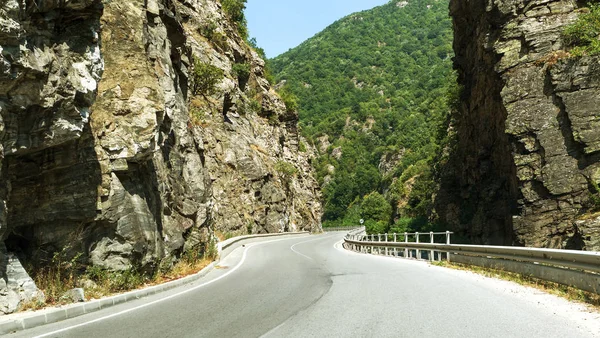 A winding mountain road. Two-way road in the mountains. Paved highway in a mountainous area near the rocky slopes of stone
