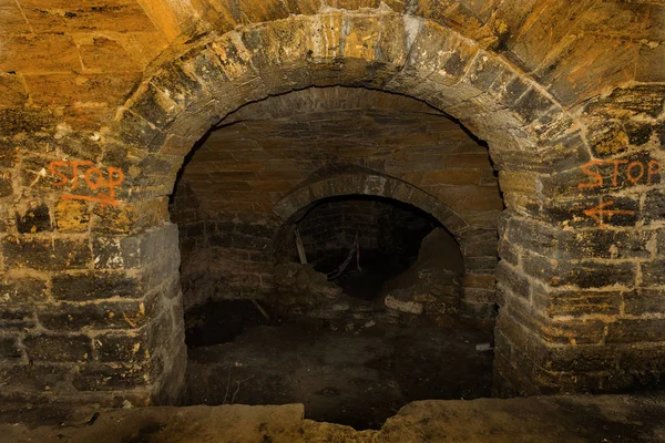 An old abandoned tunnel in an underground wine cellar. Entrance to catacombs. Dungeon Old stone fortress. As creative background for staging dark design. Mystical interior of ancient dungeon