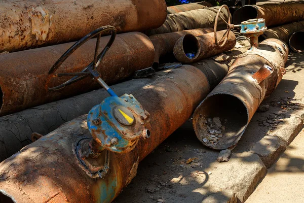 Fragments of old large water pipes. After many years of operation, destroyed metal pipe was destroyed. Vegetable steel tube with hole corrosion. Rusty metal pipe. Selective focus