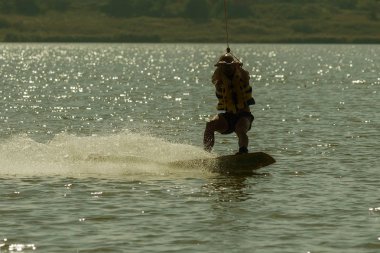 Uyku modundan çıkarma Park. Yaz plaj su sporları. Atlet gemide su kayar. Skyt su. Kaykay, Wakeboarding. Siluet özgün tasarım işlemi olan arka ışık içinde. Yaz spor arka plan