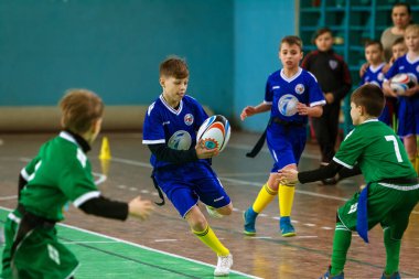 Odessa, Ukrayna - Hazi 24,2018: Küçük çocuklar kapalı salonunda şehir okulun derby Oyunlar sırasında rugby oynamak. Çocuk spor. Çocuk rugby 5 oyun. Çocuk zafer için mücadele. Sağlıklı yaşam tarzı
