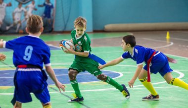 Odessa, Ukrayna - Hazi 24,2018: Küçük çocuklar kapalı salonunda şehir okulun derby Oyunlar sırasında rugby oynamak. Çocuk spor. Çocuk rugby 5 oyun. Çocuk zafer için mücadele. Sağlıklı yaşam tarzı