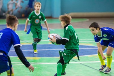 Odessa, Ukrayna - Hazi 24,2018: Küçük çocuklar kapalı salonunda şehir okulun derby Oyunlar sırasında rugby oynamak. Çocuk spor. Çocuk rugby 5 oyun. Çocuk zafer için mücadele. Sağlıklı yaşam tarzı