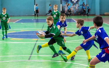 Odessa, Ukrayna - Hazi 24,2018: Küçük çocuklar kapalı salonunda şehir okulun derby Oyunlar sırasında rugby oynamak. Çocuk spor. Çocuk rugby 5 oyun. Çocuk zafer için mücadele. Sağlıklı yaşam tarzı