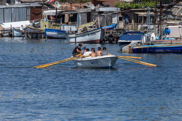 VARNA, BULGARIA - CIRCA 2017: Young athletes train in a rowing team on marine lifeboats in the water area of the port of Varna