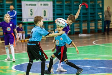 Odessa, Ukrayna - Hazi 24,2018: Küçük çocuklar kapalı salonunda şehir okulun derby Oyunlar sırasında rugby oynamak. Çocuk spor. Çocuk rugby 5 oyun. Çocuk zafer için mücadele. Sağlıklı yaşam tarzı