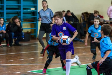 Odessa, Ukrayna - Hazi 24,2018: Küçük çocuklar kapalı salonunda şehir okulun derby Oyunlar sırasında rugby oynamak. Çocuk spor. Çocuk rugby 5 oyun. Çocuk zafer için mücadele. Sağlıklı yaşam tarzı