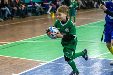 Odessa, Ukrayna - Hazi 24,2018: Küçük çocuklar kapalı salonunda şehir okulun derby Oyunlar sırasında rugby oynamak. Çocuk spor. Çocuk rugby 5 oyun. Çocuk zafer için mücadele. Sağlıklı yaşam tarzı