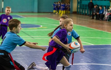Odessa, Ukrayna - Hazi 24,2018: Küçük çocuklar kapalı salonunda şehir okulun derby Oyunlar sırasında rugby oynamak. Çocuk spor. Çocuk rugby 5 oyun. Çocuk zafer için mücadele. Sağlıklı yaşam tarzı