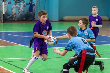 Odessa, Ukrayna - Hazi 24,2018: Küçük çocuklar kapalı salonunda şehir okulun derby Oyunlar sırasında rugby oynamak. Çocuk spor. Çocuk rugby 5 oyun. Çocuk zafer için mücadele. Sağlıklı yaşam tarzı