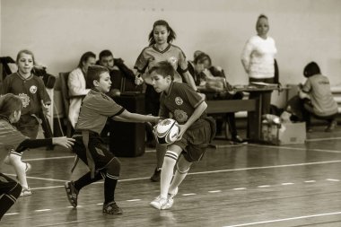 Odessa, Ukrayna - Hazi 24,2018: Küçük çocuklar kapalı salonunda şehir okulun derby Oyunlar sırasında rugby oynamak. Çocuk spor. Çocuk rugby 5 oyun. Çocuk zafer için mücadele. Sağlıklı yaşam tarzı