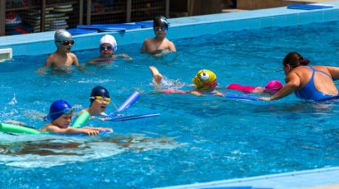 Varna, Bulgaristan - 31 Mayıs 2017: Büyüleyici mutlu çocuk çocuk yüzme havuzu ile banyo keyfini çıkarın. Koç yüzme havuzu çocuklarda öğretir. Spor çocuklar. Çocuk spor