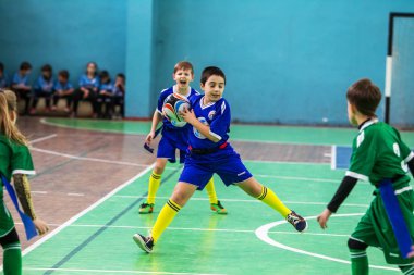 Odessa, Ukrayna - Hazi 24,2018: Küçük çocuklar kapalı salonunda şehir okulun derby Oyunlar sırasında rugby oynamak. Çocuk spor. Çocuk rugby 5 oyun. Çocuk zafer için mücadele. Sağlıklı yaşam tarzı