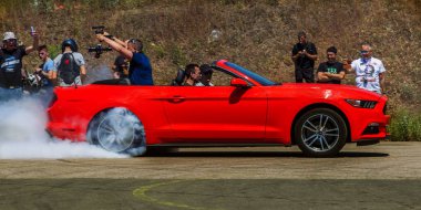 Odessa, Ukrayna - 10 Haziran 2018: Otomobil Fuarı. Aşırı hileler, motosiklet, efsanevi Mustang araba drift. Tekerlekler yere kadar ısınma gelen duman. Sitede drift. Aşırı Otomobil Fuarı önünde hız yarış