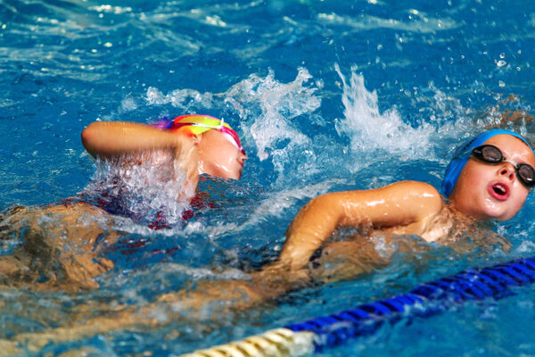 ODESSA, UKRAINE -24 September 2016: sporting swimming in pool during Ukrainian championship triathlon athletes among children. Children swimming competition in indoor pool