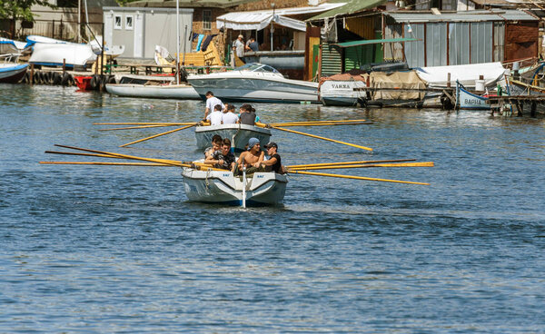 VARNA, BULGARIA - CIRCA 2017: Young athletes train in a rowing team on marine lifeboats in the water area of the port of Varna